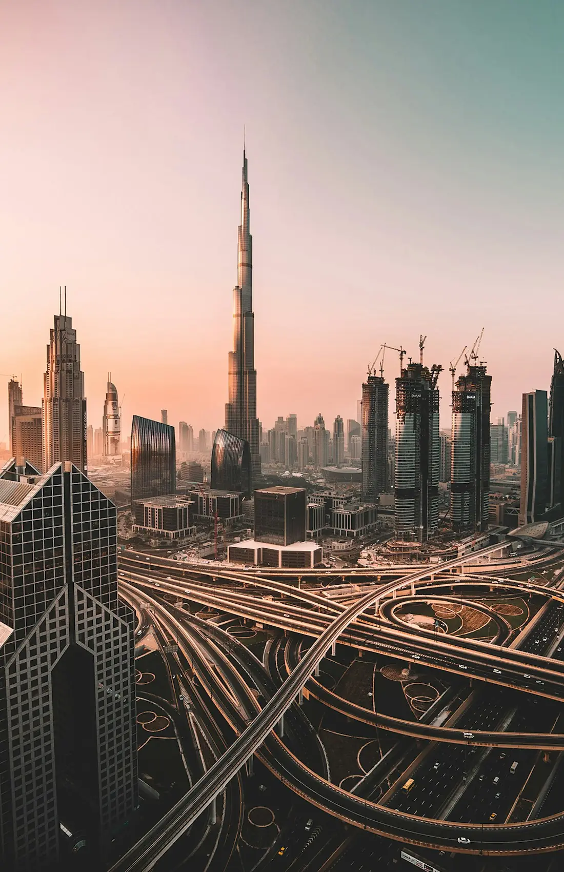 Dubai at sunset, the Burj Khalifa and Downtown towers rising above the Sheikh Zayed Road interchange